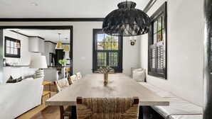 A modern dining area with a wooden table, woven chairs, and a black pendant light. - The Preserve | Barbados Lock-off | 3 BR + 3 BA (Charleston)