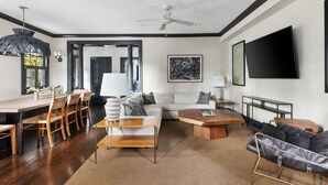 A modern living room with a dining area, a sofa, a coffee table, and a TV mounted on the wall. - The Preserve | Barbados Lock-off | 3 BR + 3 BA (Charleston)