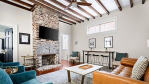 A living room with a stone fireplace, a wooden ceiling, and a large window.