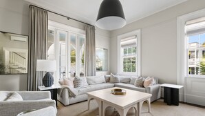A spacious living room with a large sectional sofa, a coffee table, and a view of the outside. - Downtown|3 Beds|Luxury Rental (Charleston)