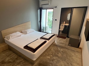 A double bed with a wooden headboard, a large window with curtains, and a bathroom visible through an open door. - Newman Hotel Donmuaeng (Lam Luk Ka)