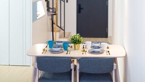 Un espace de salle à manger moderne, avec une table dressée pour deux personnes, un escalier et une porte en arrière-plan.