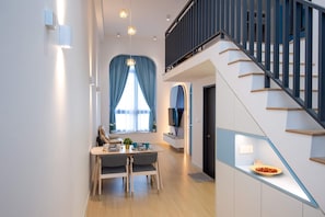 A modern interior with a dining area, staircase, and a TV mounted on the wall.