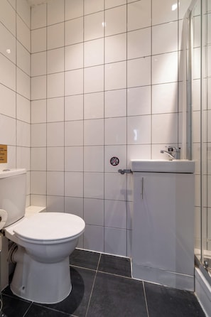 A bathroom with a white toilet, a sink, and a shower area.