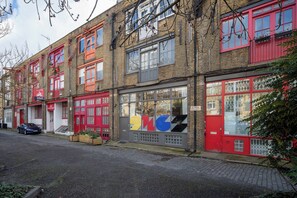 A row of red-framed buildings with large windows and a car parked in front.