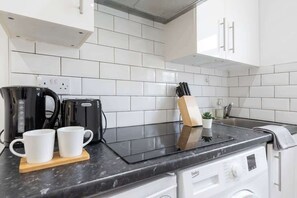 Een keuken met witte kasten, een zwart aanrecht, een koffiezetapparaat en een messenblok.