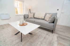 A modern living room with a white coffee table, grey sofa, and a lamp.