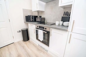 A modern kitchen with white cabinets, a microwave, a toaster, and an oven.