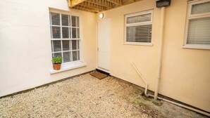 A small, enclosed outdoor area with a gravel floor, a potted plant, and a wooden staircase leading to an upper level. - Stunning 1BR Cheltenham Suite Near Town Centre (Cheltenham)
