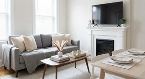 Un salon moderne avec un canapé gris, une table basse, une cheminée et un téléviseur à écran plat fixé au-dessus de la cheminée.