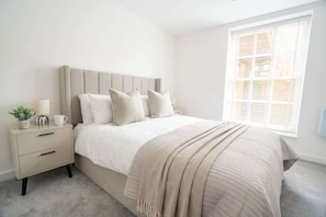 A bedroom with a bed, bedside table, and a window.
