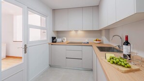 A compact kitchen with white cabinets, a wooden countertop, a sink, and a wine bottle. - Nitas Apartment (Pollença)