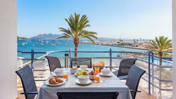 A table set for breakfast with a view of the sea and boats. - Nitas Apartment (Pollença)