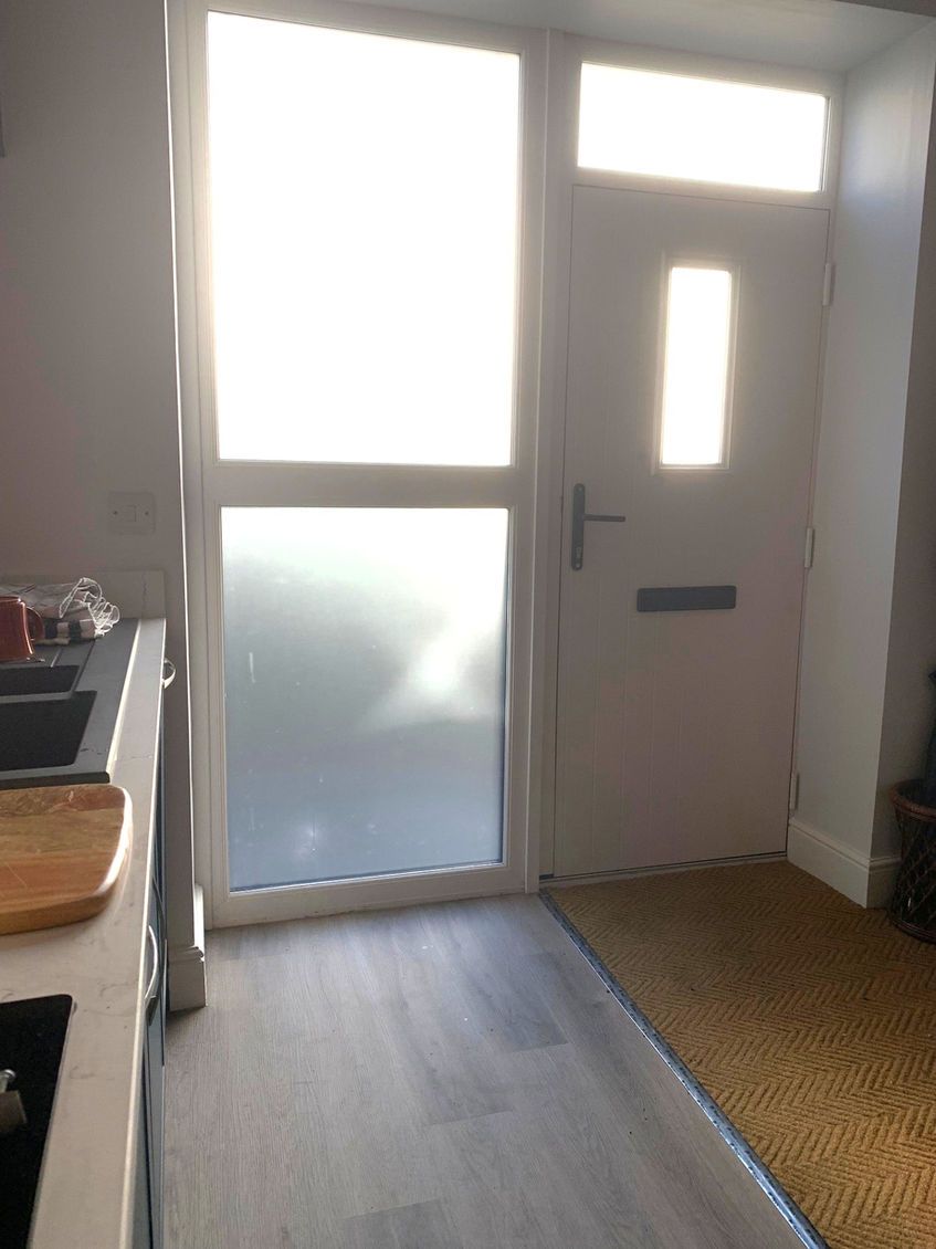 A room with a sliding glass door, a small window, and a wooden floor.