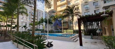 A residential building with balconies, a swimming pool, and outdoor seating areas.