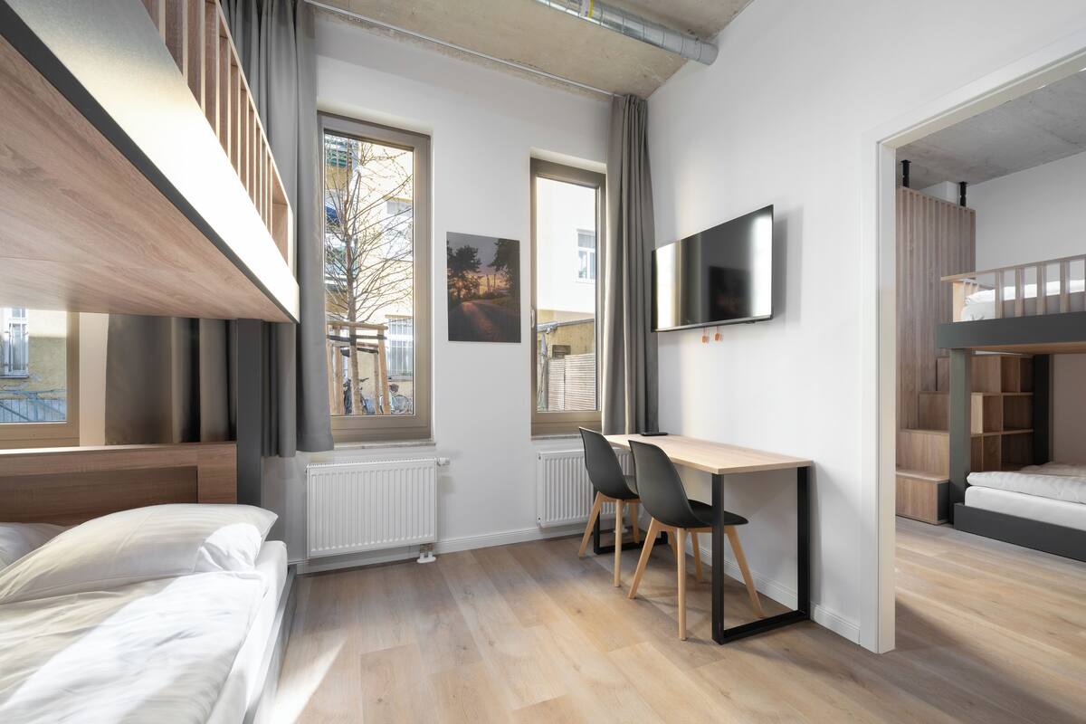 Ein modernes Schlafzimmer mit Hochbett, Schreibtisch und Fernseher.
