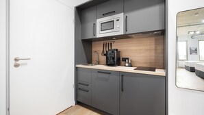 A modern kitchen with grey cabinets, a microwave, a coffee maker, and a wooden countertop. - Homaris Apartments Isartor (Munich)