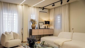 A modern living room with a glass coffee table, two sofas, a cabinet, and a TV. - Libertini Apartments by FreedomWay (Lekki)