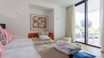 Een hotelkamer met twee bedden, een bank, een groot raam met uitzicht op de omgeving en een schilderij aan de muur.