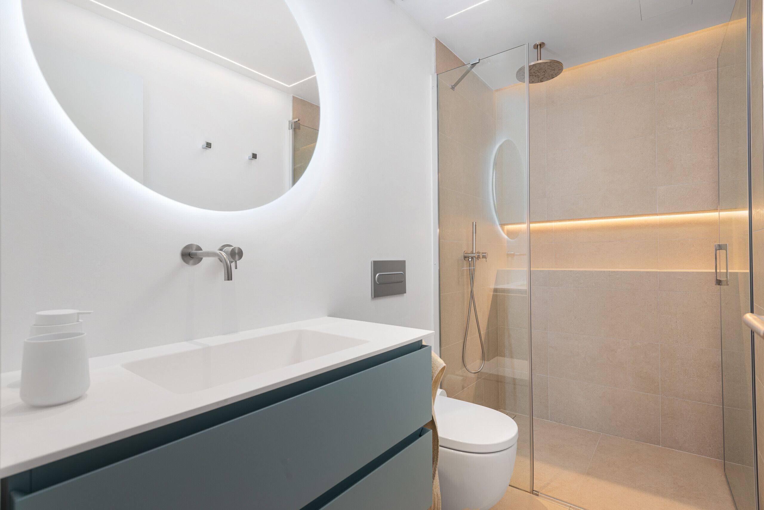 Une salle de bain moderne avec un lavabo blanc, une douche à parois de verre et des toilettes.
