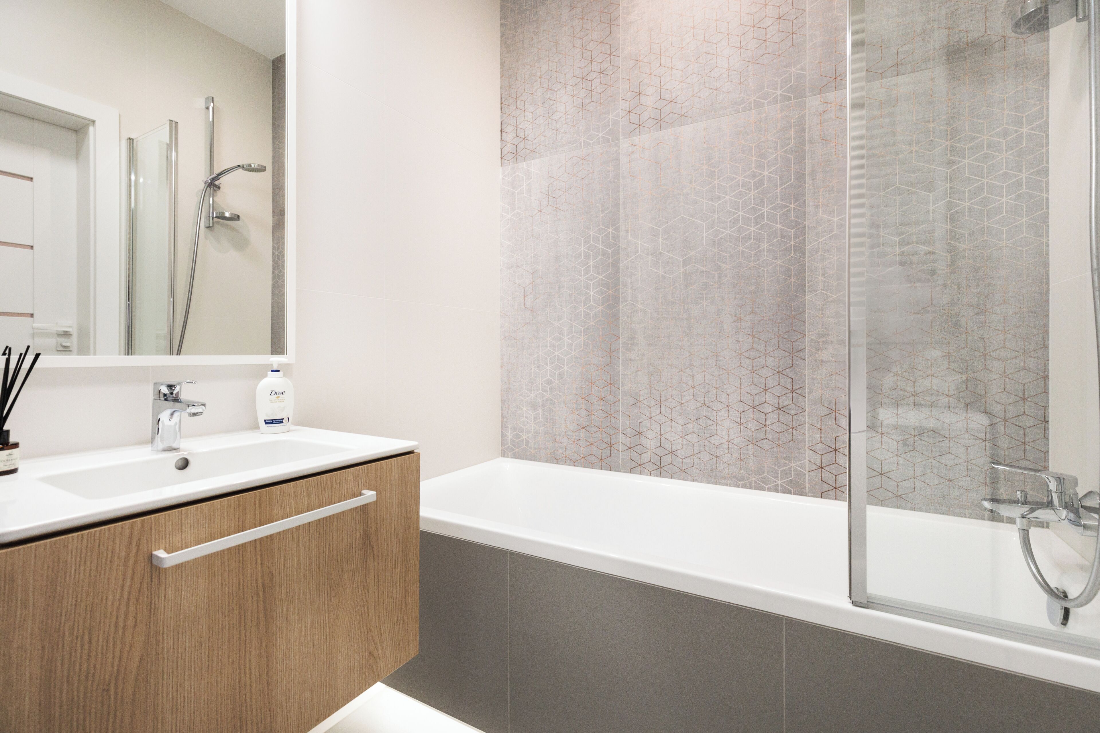 A modern bathroom with a glass shower enclosure, a wooden vanity with a sink, and a large bathtub.
