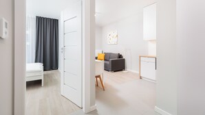 A modern, well-lit room with a bed, a desk, a sofa, and a small kitchen area. - City of the Kings-Milford Sound (Kraków)
