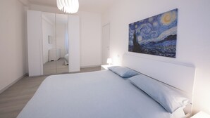 Un dormitorio moderno con una cama grande, un cuadro de un cielo nocturno y un espejo en el armario.
