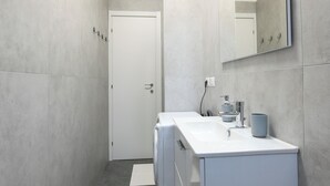 Un baño moderno con un tocador blanco, un espejo y un perchero para toallas.
