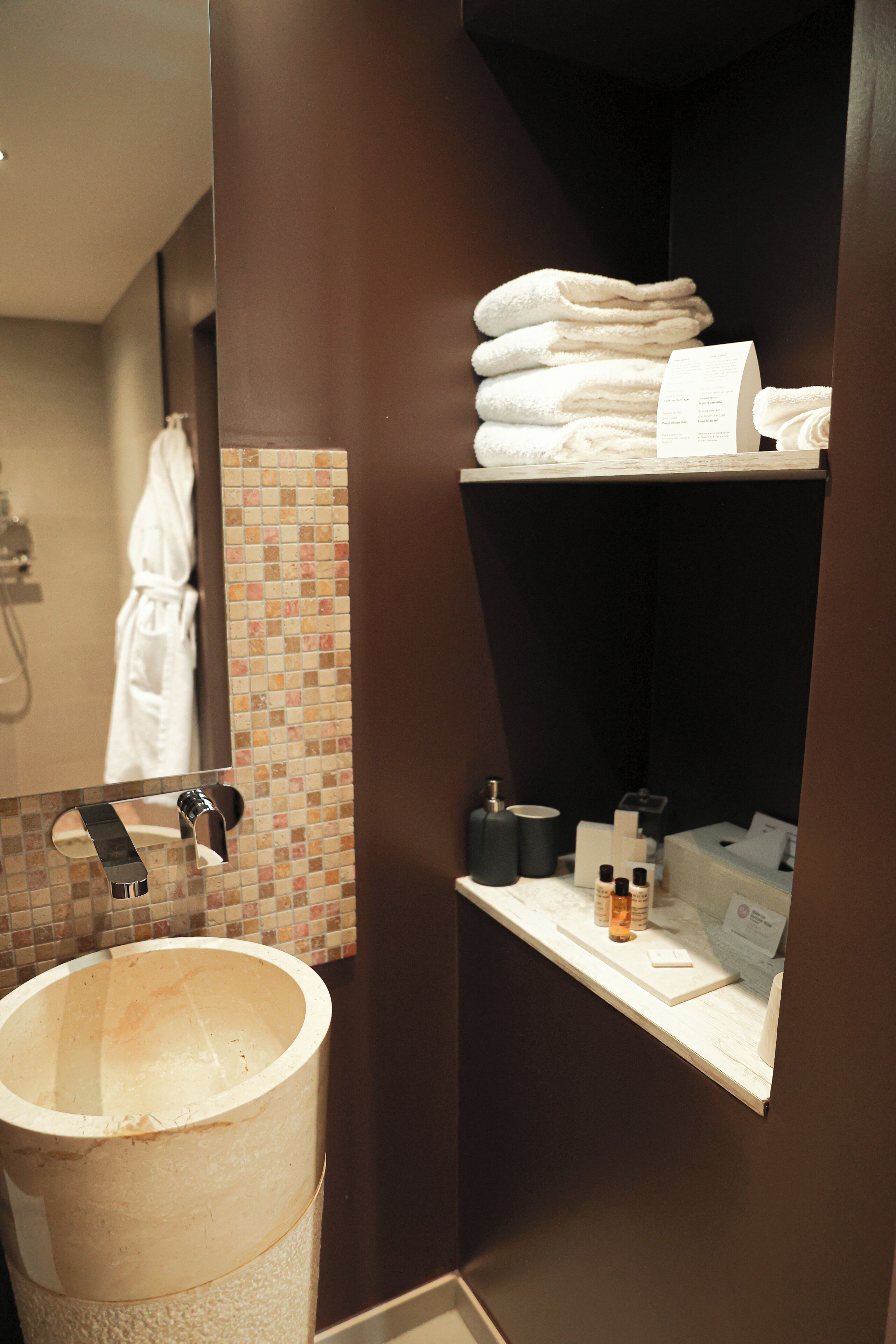 Une salle de bain équipée d’un lavabo, d’un miroir, d’un porte-serviettes et d’une étagère contenant des articles de toilette.