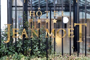 A hotel sign with the name "HOTEL JEAN MOET" in large golden letters, surrounded by greenery. - Hôtel Jean Moët (Épernay)