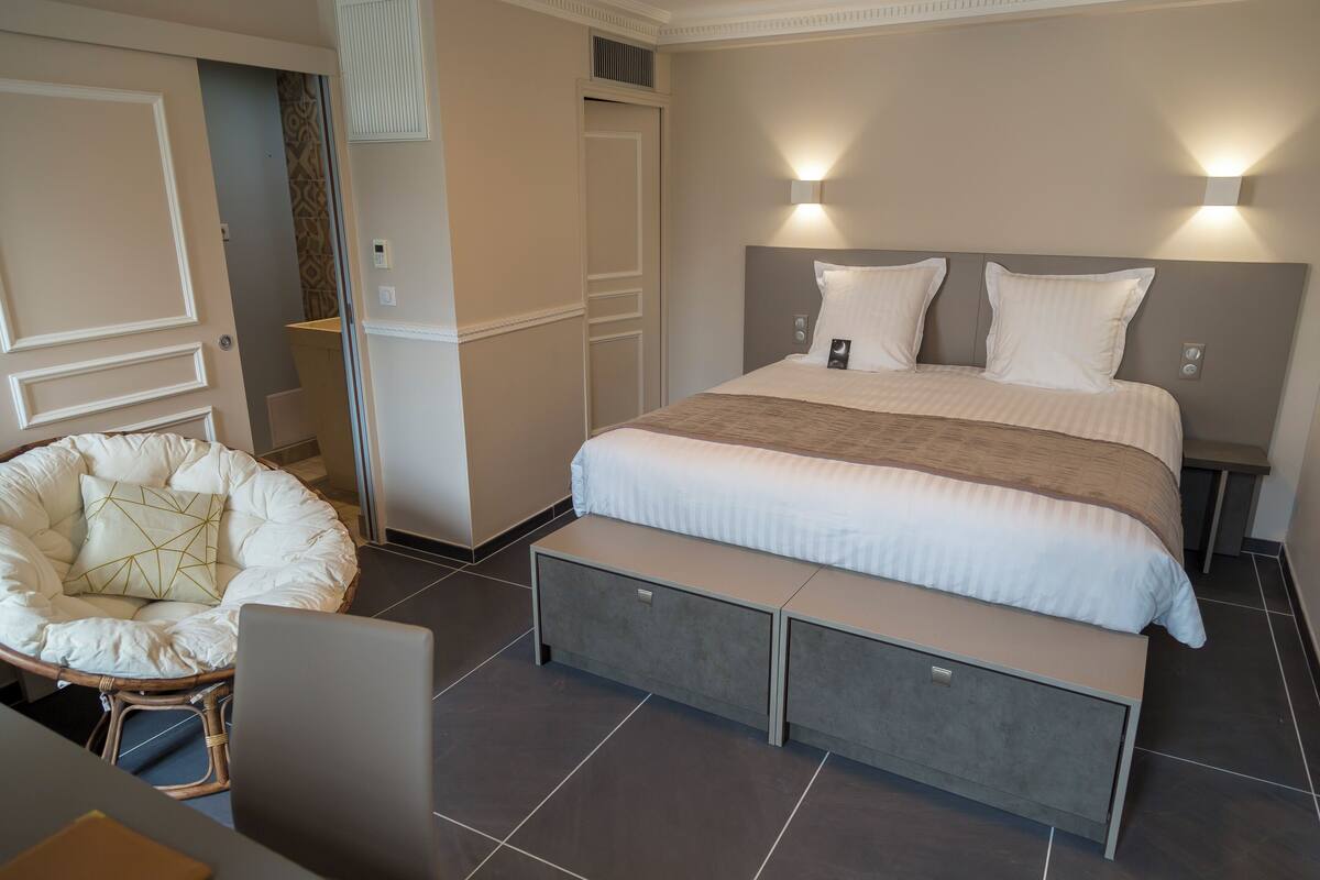 A bedroom with a bed, bedside tables, a chair, and a bench.