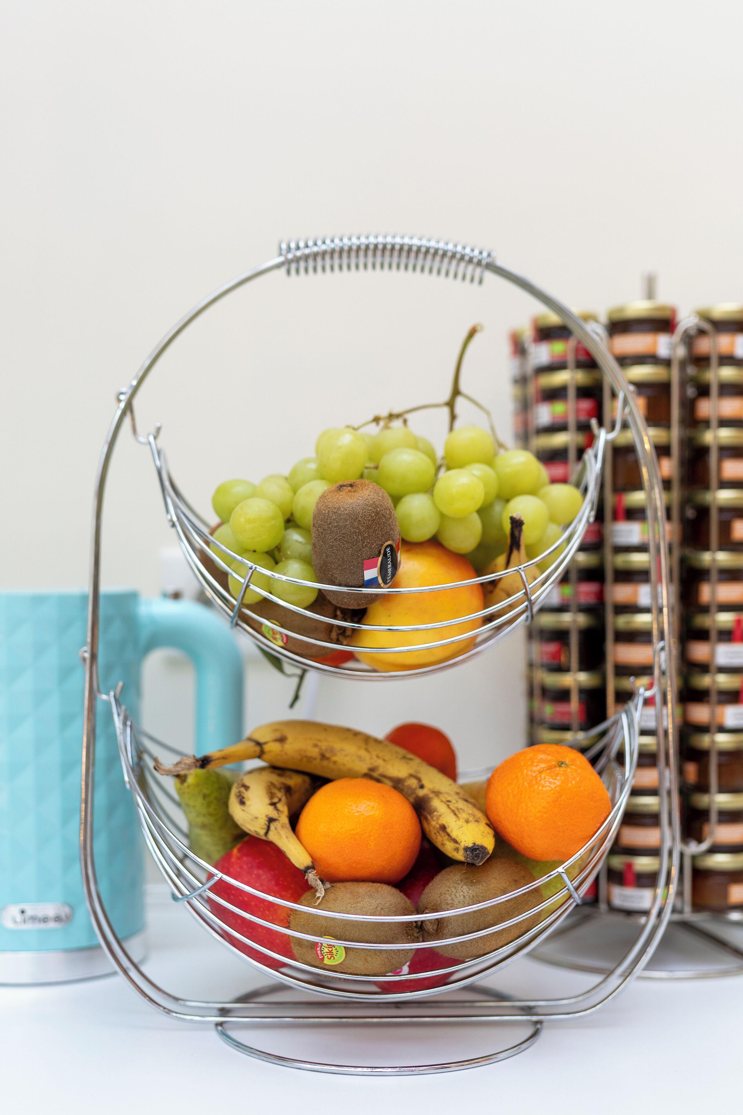 Una cesta de frutas con manzanas, plátanos, naranjas y uvas.