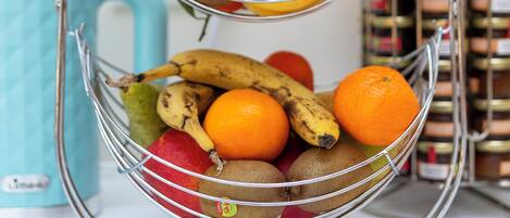 Una cesta de frutas con manzanas, plátanos, naranjas y uvas.