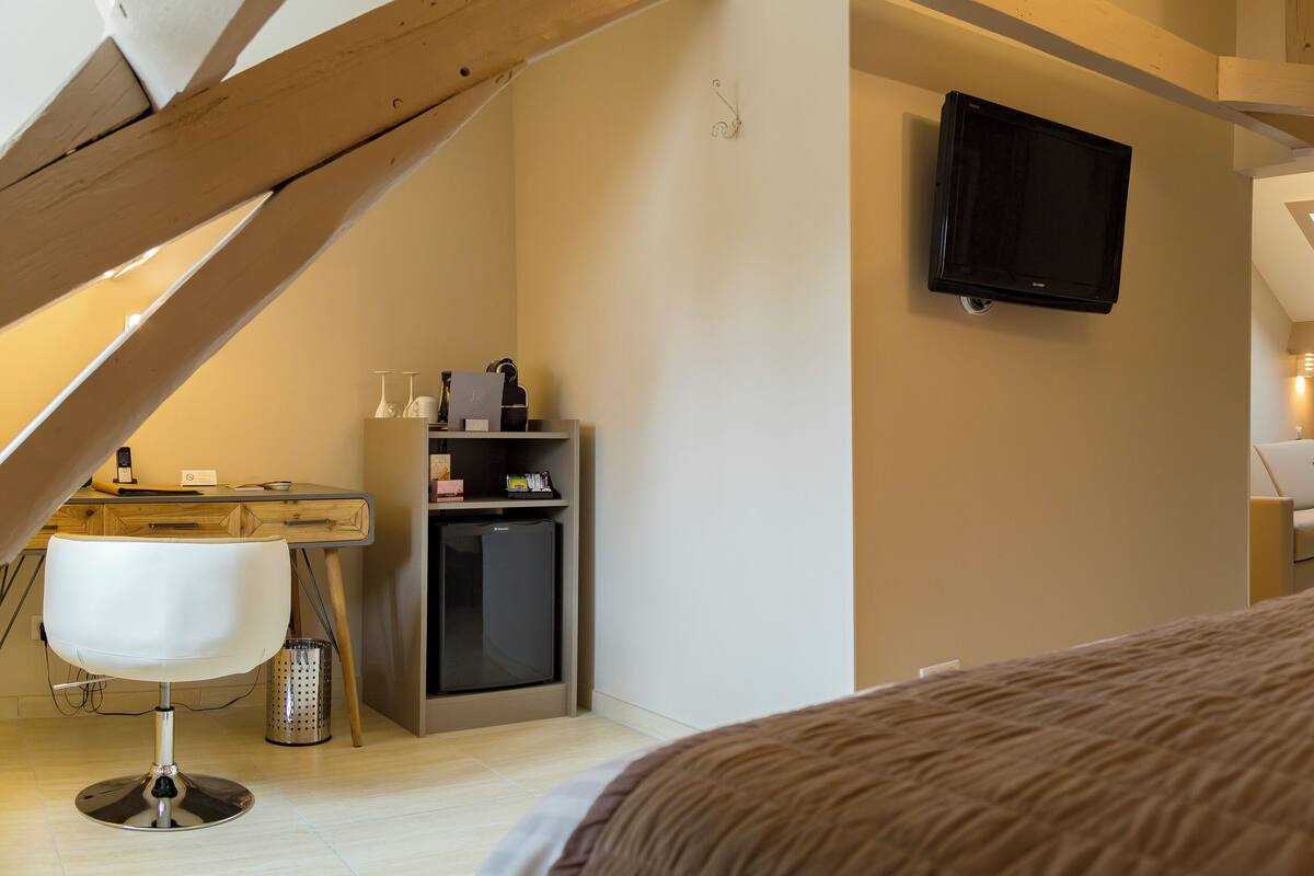 A bedroom with a large bed, a TV mounted on the wall, and a skylight.