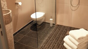 A modern bathroom with a glass shower enclosure, a toilet, and a sink with a towel rack. - Hôtel Jean Moët (Épernay)
