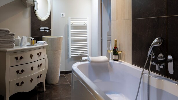 A modern bathroom with a freestanding bathtub, a vanity with drawers, a large mirror, and a skylight. - Hôtel Jean Moët (Épernay)