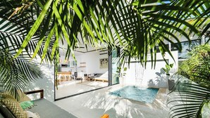 A modern indoor pool area with a glass wall, surrounded by lush greenery and comfortable seating. - Luxury This 2-bed, 2-bath villa with Exclusive access to the Langosta Beach Club (Tamarindo)