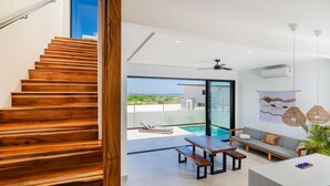 Ein modernes Interieur mit einer Holztreppe, einem Balkon mit Pool und einer Sitzecke mit Tisch und Bank.