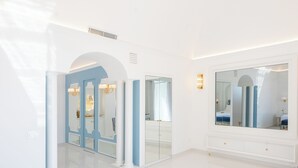A modern, well-lit bedroom with a large mirror, a vanity, and a bed with a blue accent. - La Sirenetta Luxury Suite Positano (Positano)