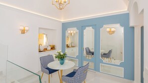 A dining area with a round table, blue patterned chairs, and a vase with flowers. - La Sirenetta Luxury Suite Positano (Positano)