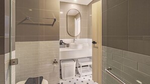 Un baño moderno con cabina de ducha de vidrio, un lavamanos blanco, un espejo y un perchero para toallas.