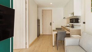 Cocina compacta con comedor, televisor y puerta que da a otra habitación.