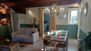 Een gezellige woonkamer met een bank, een eettafel gedekt voor vier personen en een kroonluchter.