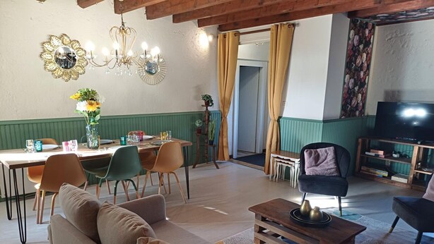 Een woonkamer met een bank, salontafel en tv-meubel. Er is een eethoek met stoelen en een tafel.