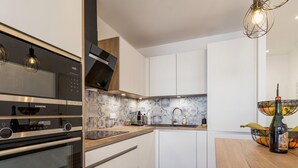 A modern kitchen with white cabinetry, a built-in oven, and a wooden countertop.