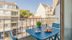 A balcony with a table and chairs, a potted plant, and a plate with croissants.
