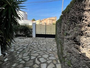 Secure entrance to a well-maintained property with a metal gate and lush hedge.