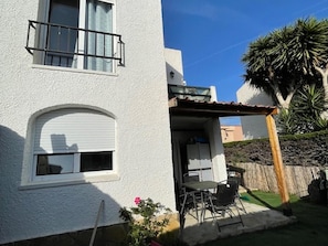 Enjoy a balcony with a patio area featuring a table and chairs, surrounded by a garden.