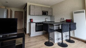 A compact kitchen with a microwave, stove, and bar stools.