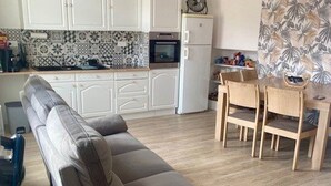 Eine moderne Küche mit weißen Schränken, einem eingebauten Backofen und einem Essbereich mit Holzkästen.